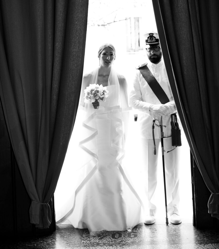 Foto in bianco e nero sposa che entra in chiesa accompagnata da militare in divisa della marina Civitanova Marche Monica Palloni fotografa