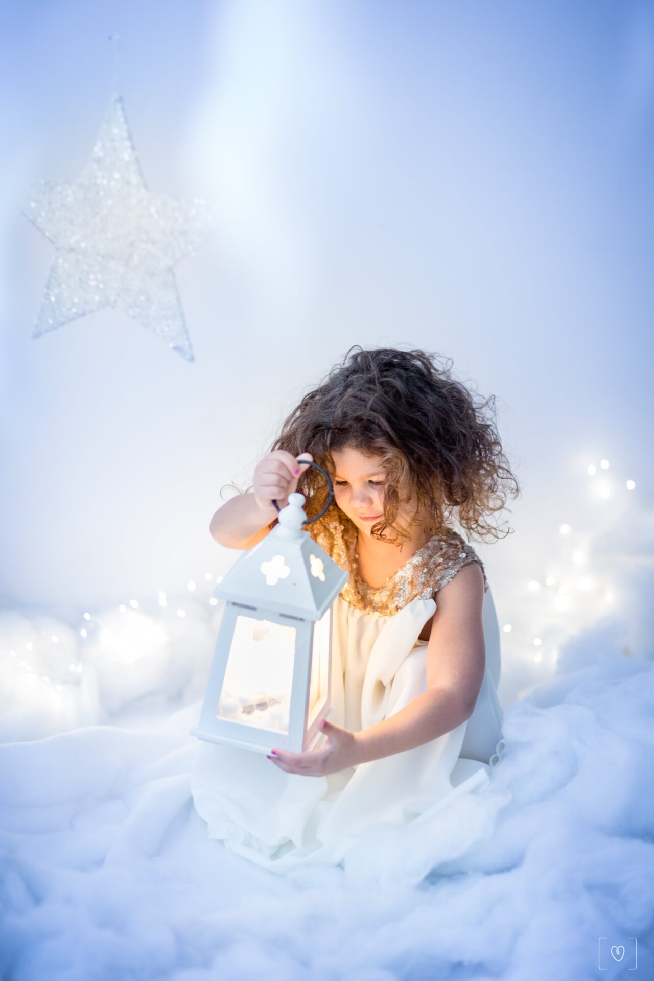 Foto di bambina che tiene una lanterna accesa durante servizio fotografico di Natale con neve a Civitanova Marche set bianco Monica Palloni Fotografa